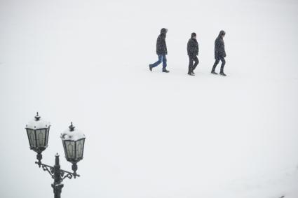 Трое мужчин идут по заснеженной площади.