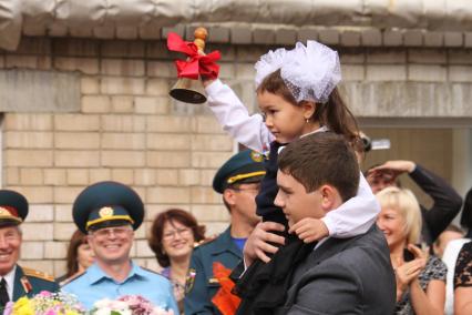 Девочку с школьным колокольчиком несет на руках старшеклассник.