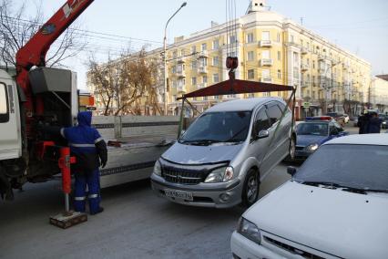 Эвакуатор грузит автомобиль под присмотром сотрудников ДПС ГИБДД.