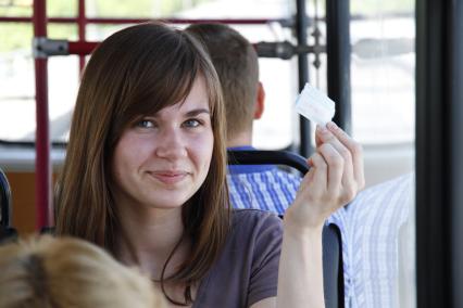 Девушка с билетом в руках в троллейбусе.
