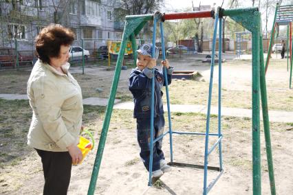 Женщина с ребенком на детской площадке.