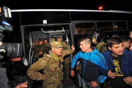 Ситуация в Донецке. У военкомата местные жители перекрыли дорогу автобусу с украинскими номерами, в котором находились военные с оружием без  опознавательных знаков. На снимке: военные выходят из автобуса и направляются в здание военкомата.