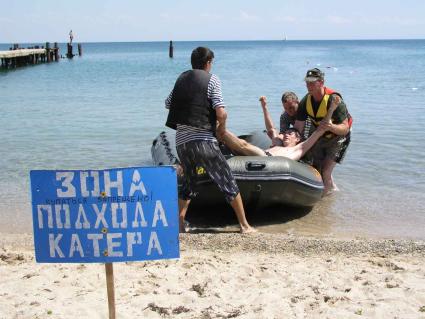 Отдых в Крыму. Спасательная станция. На снимке: спасатели вытаскивают мужчину из катера.