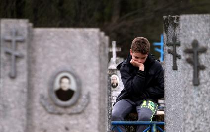 Мальчик сидит на кладбище.