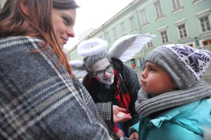 Женщина с ребенком и мужчина в костюме купидона.