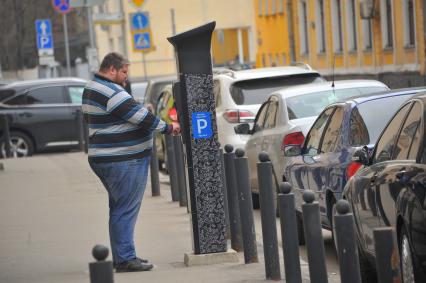 Мужчина оплачивает парковку.