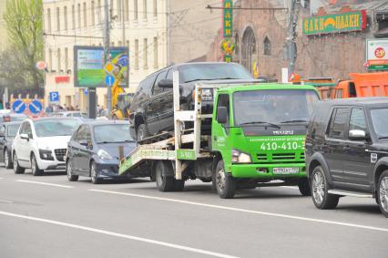 Эвакуатор везет машину по городу.