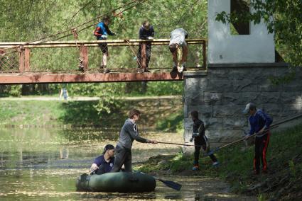 парень стоя в резиновой надувной лодке чистит городской пруд на субботнике в Харитоновском саду в Екатеринбурге