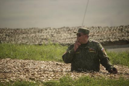 Российский военный офицер курит стоя в окопе во времфя учений на полигоне в Чебаркуле