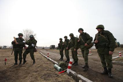 Солдаты на учениях. Старшина поправляет форму новобранцу