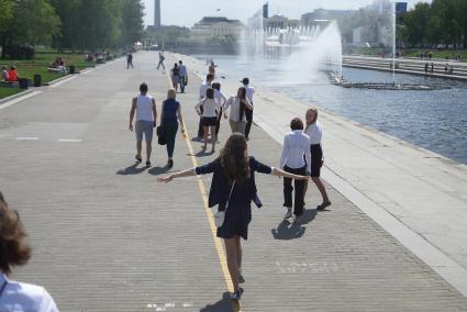 Выпускница бежит по набережной во время празднования последнего звонка в школах