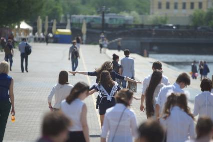 Выпускницы бегут по набережной  во время празднования последнего звонка в школах