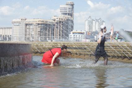 Выпускницы играют в воде в фонтане во время празднования последнего звонка