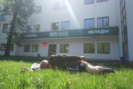 Бродяга спит на газоне перед входом в ВУЗ-банк