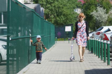 Мама с сыном идут вдоль забора