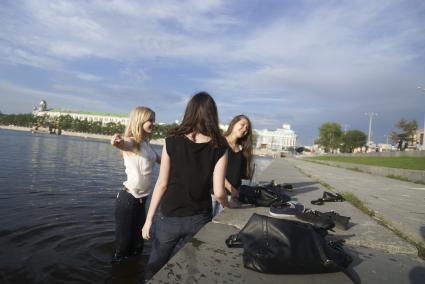 три девушки стоят в воде около набережной