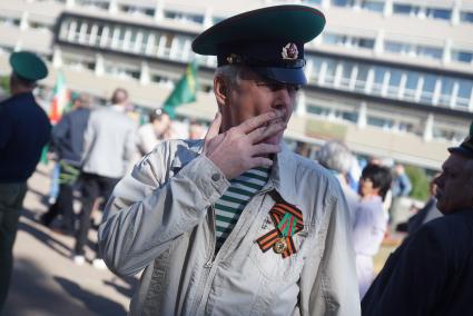 Мужчина в зеленой фуражке, зеленой тельняжке и с георгиевской лентой во время празднования дня пограничкика