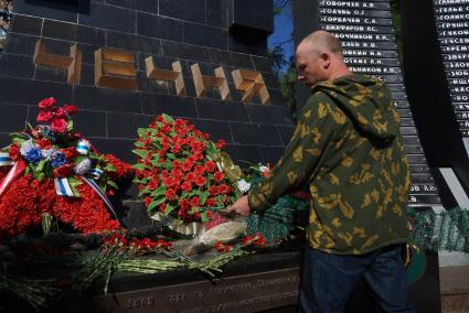 мужчина в зеленой камуфляжной куртке возлагает цветы к памятнику \"черный тюльпан\" в Екатеринбурге во время дня пограничника