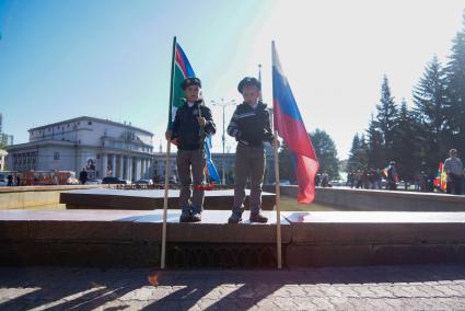 Два мальчика в зеленых беретах тосят с флагапи пограничных войск и РФ