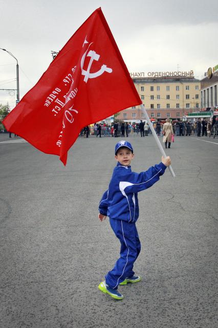 Мальчик с красным знаменем во время празднования годовщины Победы в Барнауле.