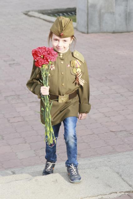 Празднование годовщины Победы в Барнауле. Ребенок в военной форме с цветами в руках.
