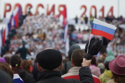 Мужчина машет российским флажком во время выступления сводного хора из 1000 человек под дождем во время празднования дня России