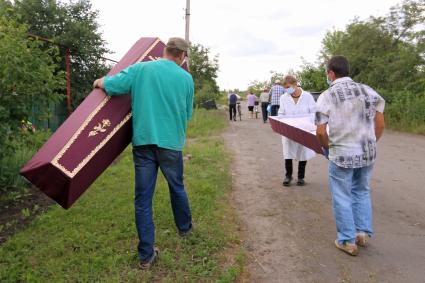 Поселок Восточный, подвергшийся ночью артобстрелу украинской армии. Погибли 3 пенсионера. На снимке: волонтеры несут гроб.