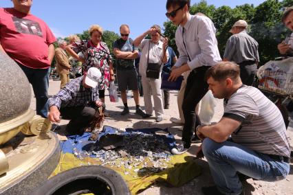 Луганск. Здание Луганской областной администрации после авианалета украинской армии. На снимке: люди собирают осколки снарядов на украинский флаг.