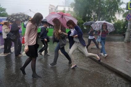 Девушки перепрыгивают широкие лужи во время дождя