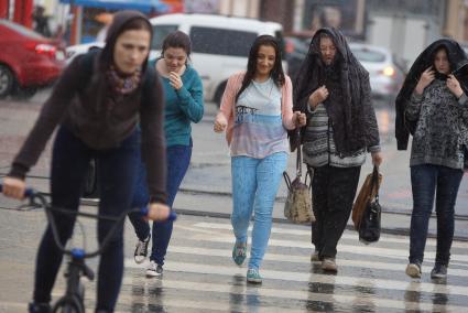 девушки идут через дорогу во время дождя