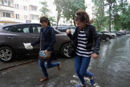 две девушки бегут по лужам морщась от дождя