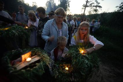 Участники празднования дня Ивана Купала стоят с венками в руках, перед их спуском на воду