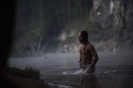 Участник празднования дня Ивана Купала выходит из воды после спуска венков.