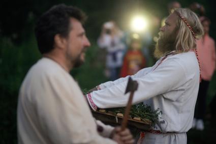 Участник празднования дня Ивана Купала стоит с венком в руках, перед его спуском на воду