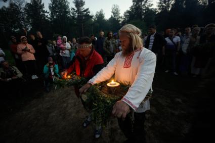 Участники празднования дня Ивана Купала стоят с венками в руках, перед их спуском на воду