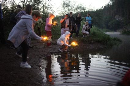Участник празднования дня Ивана Купала пускают венки на воду