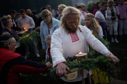 Участники празднования дня Ивана Купала стоят с венками в руках, перед их спуском на воду