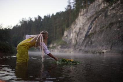 Участница празднования дня Ивана Купала спускает на воду венок