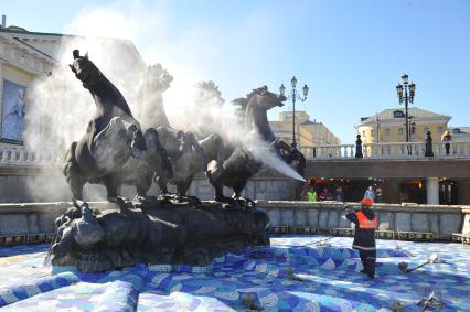 Манежная площадь. На снимке: сотрудник коммунальной службы города моет скульптурную группу `Времена года` фонтана `Гейзер`.