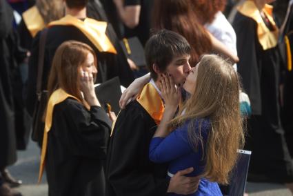 Выпускник УрФУ в черной мантии с следом от поцелуя на щеке обнимает и целует дувушку