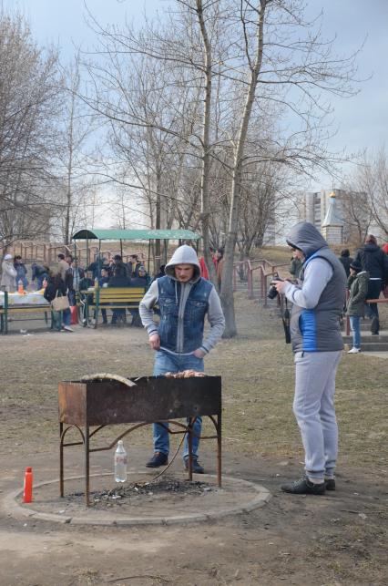 Парк `Северное Тушино`. На снимке: молодые люди жарят шашлык на мангале.