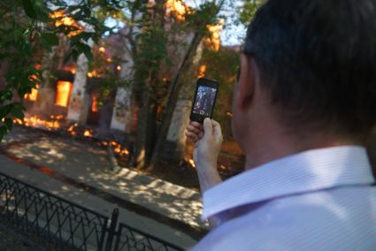Мужчина снимает пожар в доме на сотовый телефон