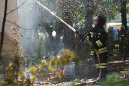 Пожарный из брандспойта тушит огонь в доме