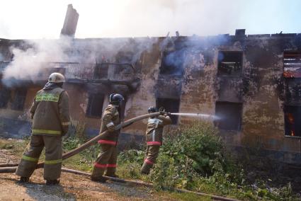 Пожарный тушит горящий дом в Екатеринбурге