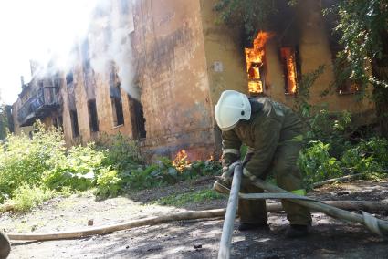 Пожарный распутывает пожарные рукава во время  пожара в доме в Екатеринбурге