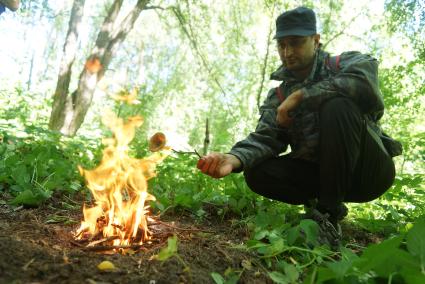 Мужчина грибник жарит гриб на костре