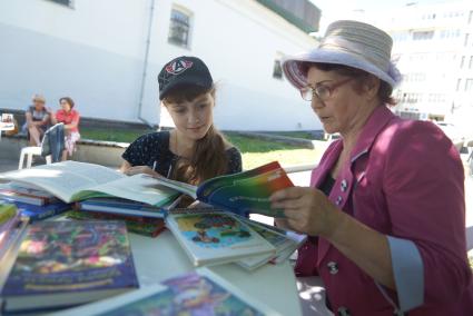 бабушка с внучкой читают книгу в библиотеке под открытым небом  в Екатеринбурге