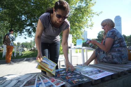 женцина раскладывает книги на столе библиотеки под открытым небом в Екатеринбурге
