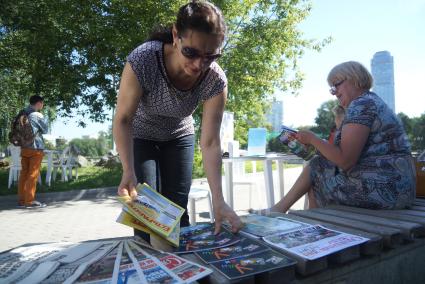 женцина раскладывает книги на столе библиотеки под открытым небом  в Екатеринбурге