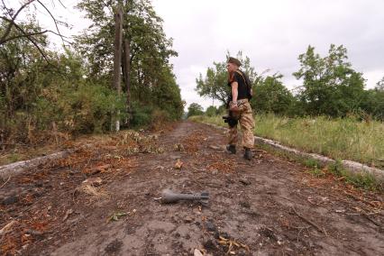 Село Семеновка. Украинская армия обстреляла село запрещенными фосфорными минами. Подобные использовались в Сирии. На снимке: мина, внешне обычная 120-миллиметровая мина, но с кассетной боеголовкой, начиненной фосфорным зажигательным веществом. Справа - ополченец с позывным `Моторола`.